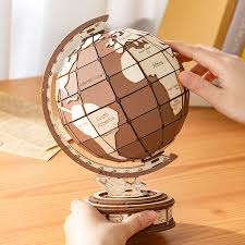 Diy 3D astronomical wooden globe model held by a hand on a wooden surface